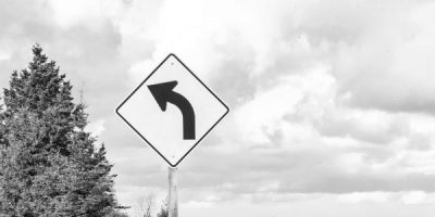 Directional arrow sign with trees and clouds in background