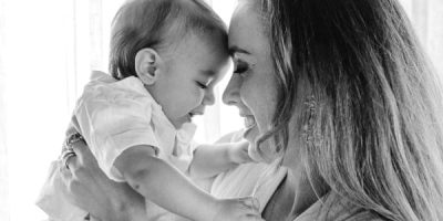 Mother with long hair holding her child closely whilst smiling